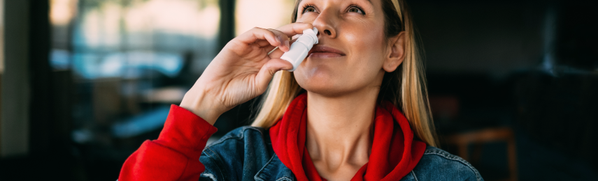 Giovane donna che utilizza lo spray nasale