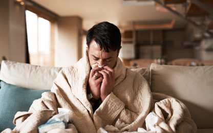 Uomo raffreddato soffia il naso sotto una coperta