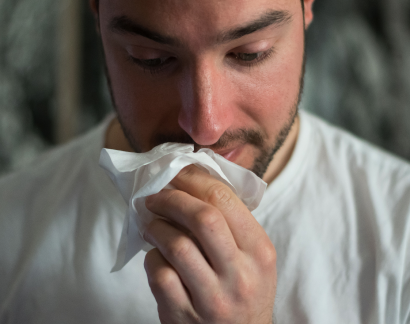 Giovane uomo che soffia il naso