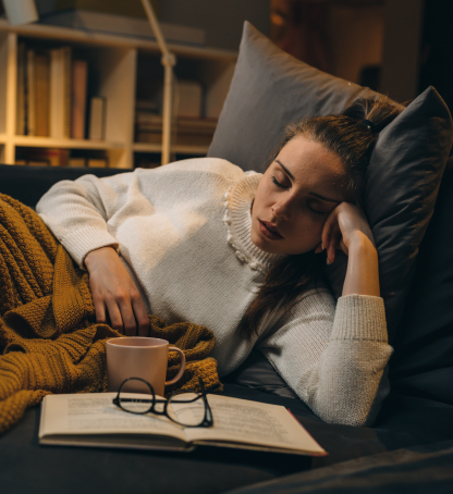 Giovane donna dorme sul divano dopo aver letto un libro
