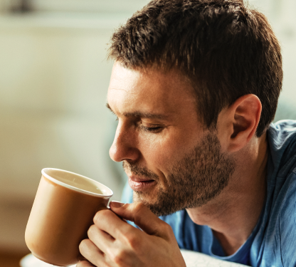 Uomo che soffia all' interno della tazza per raffreddarne il contenuto