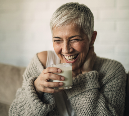 Signora di mezza età sorridente che beve del latte