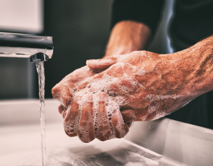 Mani di un soggetto anziano insaponate sotto l'acqua del rubinetto